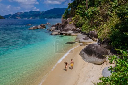 Photo for Couple of men and woman on the beach of Ko Adang Island in front of Koh Lipe Island Southern Thailand with turqouse colored ocean and white sandy beach, drone view from above - Royalty Free Image