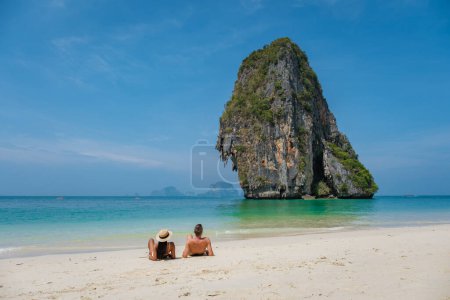 Photo for A couple of men and woman lying down on the beach of Railay Beach Krabi Thailand - Royalty Free Image