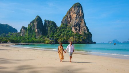 Foto de Un par de hombres y mujeres caminando por la playa de Railay Beach Krabi Tailandia, una playa tropical de Railay Krabi, una diversa pareja multirracial caminando de la mano juntos en la playa - Imagen libre de derechos