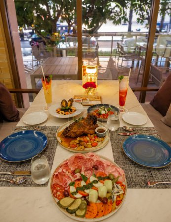 Foto de Mesa de cena en un restaurante italiano en Tailandia, antipasti con cerdo y pizza - Imagen libre de derechos