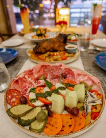 Foto de Mesa de cena en un restaurante italiano en Tailandia, antipasti con cerdo asado y pizza - Imagen libre de derechos