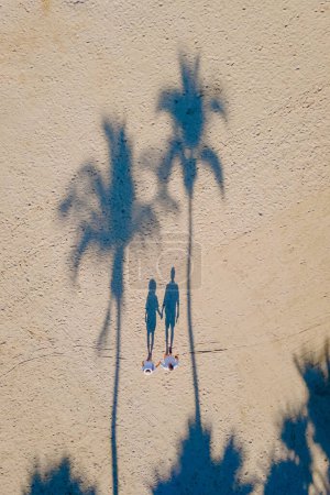 Photo for Drone view from above at a couple of men and women walking on the beach with palm trees on the beach road of Pattaya Thailand, palm tree shadow on the beach - Royalty Free Image