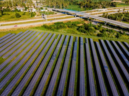 Foto de Campo de paneles solares de energía solar cerca de una carretera con tráfico, paneles solares generadores de energía del sistema del sol. Transición energética en Chonburi Tailandia - Imagen libre de derechos