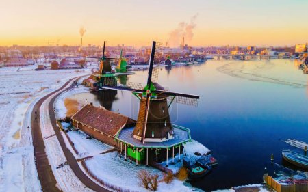 Photo for Snow covered windmill village in the Zaanse Schans Netherlands, historical wooden windmills in winter Zaanse Schans Holland during winter weather at sunrise - Royalty Free Image