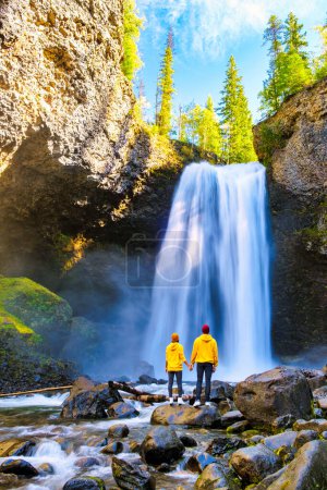 Téléchargez les photos : Moul Falls Canada ia Belle cascade au Canada, Quelques visites à Moul Falls, la cascade la plus célèbre dans le parc provincial Wells Gray. un couple d'hommes et de femmes debout près d'une cascade - en image libre de droit