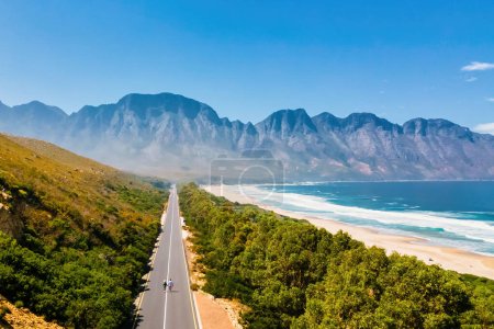 Photo for Kogelbay Beach Western Cape South Africa, Kogelbay Rugged Coast Line with spectacular mountain road. Garden Route. couple of men and women walking on the road, drone aerial view - Royalty Free Image