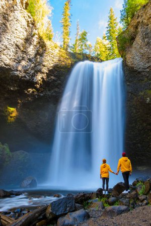 Photo for Moul Falls Canada is a Beautiful waterfall in Canada, A couple visits to Moul Falls the most famous waterfall in Wells Gray Provincial Park. a couple of men and women standing by a waterfall - Royalty Free Image