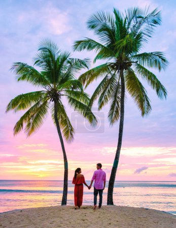 Photo for Couple on the beach with palm trees watching the sunset at the tropical beach of Saint Lucia or St Lucia Caribbean. men and women on vacation in St Lucia a tropical island in the Caribbean - Royalty Free Image