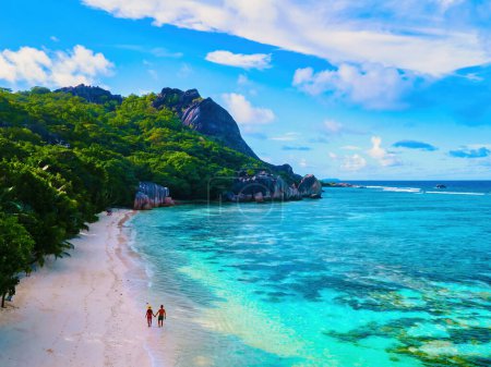 Téléchargez les photos : Anse Source d'Argent plage, île de La Digue, Seychelles, couple hommes et femmes marchant sur la plage au coucher du soleil lors de vacances de luxe aux îles tropicales des Seychelles - en image libre de droit