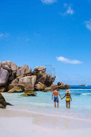 Téléchargez les photos : Anse Cocos plage La Digue Island, Seychelles, divers mixte multiracial couple hommes caucasiens et asiatique femme marche à la plage pendant le coucher du soleil - en image libre de droit
