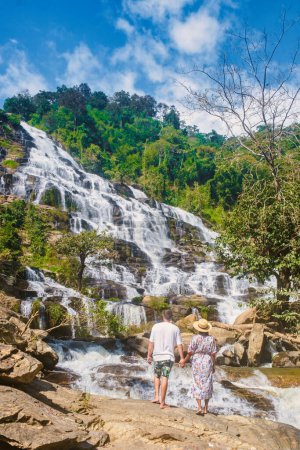 Photo for A couple of visits Mae Ya Waterfall Doi Inthanon National Park Thailand Chiang Mai during vacation. Asian women and caucasian men visit a waterfall - Royalty Free Image