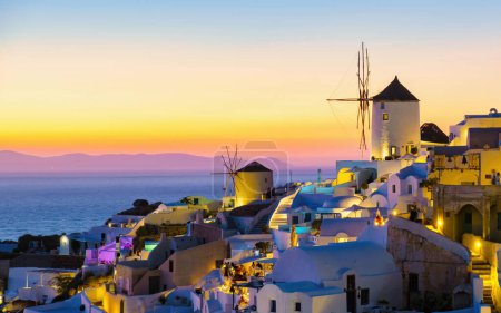 Foto de Iglesias blancas y cúpulas azules junto al océano de Oia Santorini Grecia durante la puesta del sol, un pueblo griego tradicional en Santorini durante el verano por la noche - Imagen libre de derechos