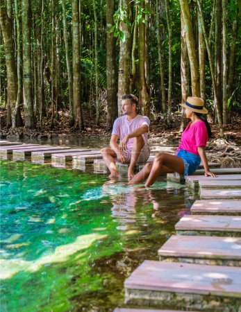 Téléchargez les photos : Un couple d'hommes et de femmes visitent la piscine d'émeraude et l'étang bleu à Krabi en Thaïlande, la lagune tropicale dans un parc national avec des arbres, et des mangroves avec de l'eau cristalline - en image libre de droit