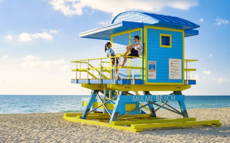 Foto de Miami Beach, una pareja en la playa de Miami Florida, una cabaña de salvavidas en Miami, mujeres asiáticas y hombres caucásicos en la playa al atardecer. hombre y mujer relajándose en una cabaña de salvavidas mirando al océano - Imagen libre de derechos