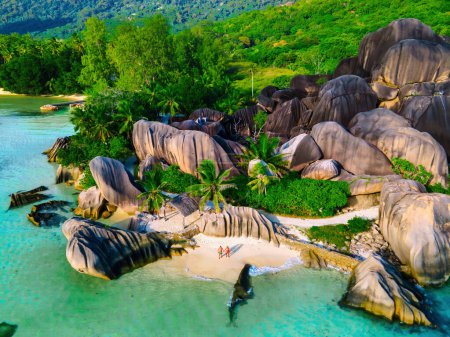 Téléchargez les photos : Un jeune couple d'hommes et de femmes sur une plage tropicale pendant des vacances de luxe aux Seychelles. Plage tropicale Anse Source d'Argent, La Digue Seychelles par une journée ensoleillée - en image libre de droit
