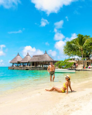 Téléchargez les photos : Homme et Femme sur une plage tropicale à Maurice, un couple en vacances de lune de miel à Maurice par une journée ensoleillée avec turque couleur océan - en image libre de droit