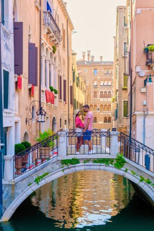 Foto de Un par de hombres y mujeres en un viaje por la ciudad en Venecia Italia sentado en un puente en Venecia, Italia. Arquitectura y punto de referencia de Venecia - Imagen libre de derechos