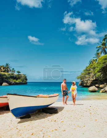 Photo for A couple of men and women in swimshorts and bikinis at Playa Lagun Beach Curacao, a couple on a vacation summer holiday in Curacao - Royalty Free Image