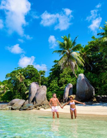 Foto de Playa Anse Royale, un par de hombres y mujeres de vacaciones en Seychelles caminando por la playa, playa tropical Mahe Seychelles con palmeras y un océano azul - Imagen libre de derechos