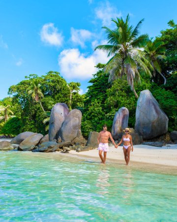 Photo for Anse Royale beach, a couple of men and women on vacation in Seychelles walking at the beach, Mahe Seychelles tropical beach with palm trees and a blue ocean at Mahe Seychelles. - Royalty Free Image