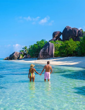 Téléchargez les photos : Anse Source d'Argent plage, Île de La Digue, Seychelles, couple hommes et femmes se relaxant à la plage lors de vacances de luxe aux Seychelles - en image libre de droit