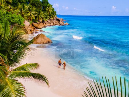 Téléchargez les photos : Anse Patates Beach La Digue Island Seychelles, Drone vue aérienne de La Digue Seychelles vue aérienne d'une île tropicale, couple hommes et femmes marchant sur la plage pendant le coucher du soleil lors de vacances de luxe - en image libre de droit
