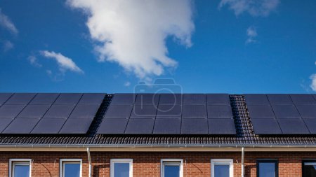 Foto de Casas de nueva construcción con paneles solares unidos al techo y paneles fotovoltaicos en el techo. Techo de paneles solares. - Imagen libre de derechos