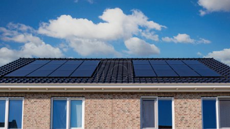 Téléchargez les photos : Maisons nouvellement construites avec des panneaux solaires noirs sur le toit contre un ciel ensoleillé Gros plan du nouveau bâtiment avec des panneaux solaires noirs. Zonnepanelen, Zonne energie, Traduction : Panneau solaire, Énergie solaire - en image libre de droit