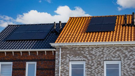 Photo for Newly built houses with solar panels attached to the roof against a sunny sky. black solar panels on a roof - Royalty Free Image