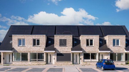 Téléchargez les photos : Maisons nouvellement construites avec des panneaux solaires fixés sur le toit contre un ciel ensoleillé, Gros plan du nouveau bâtiment avec des panneaux solaires noirs. Zonnepanelen, Zonne energie, Traduction : Panneau solaire, Énergie solaire - en image libre de droit
