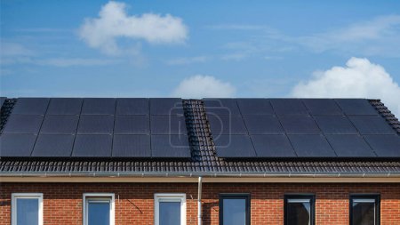 Foto de Casas de nueva construcción con paneles solares unidos en el techo contra un cielo soleado en los Países Bajos - Imagen libre de derechos