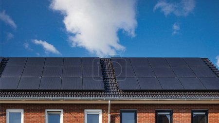 Foto de Casas de nueva construcción con paneles solares adosados en el techo Primer plano de un edificio nuevo con paneles solares negros. - Imagen libre de derechos