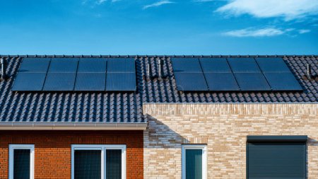 Foto de Casas de nueva construcción con paneles solares negros unidos al techo, paneles fotovoltaicos en el techo, transición de energía solar verde en los Países Bajos - Imagen libre de derechos