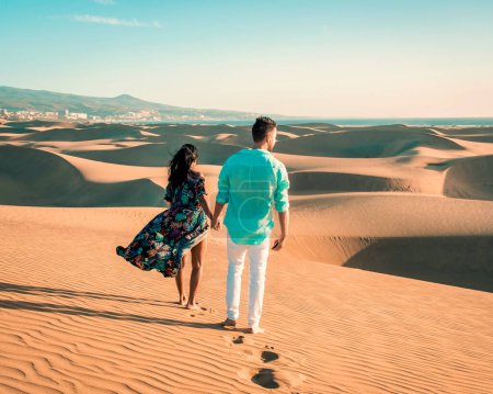 Photo for Couple walking at the beach of Maspalomas Gran Canaria Spain, men and woman at the sand dunes desert of Maspalomas Spain Europe during sunrise, couple on vacation in Spain - Royalty Free Image