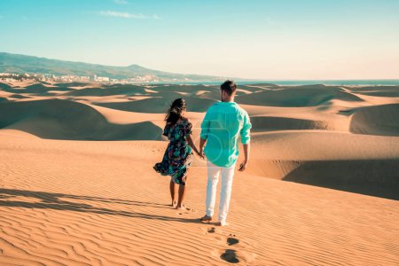 Photo for Couple walking at the beach of Maspalomas Gran Canaria Spain, men and woman at the sand dunes desert of Maspalomas Spain Europe during vacation - Royalty Free Image