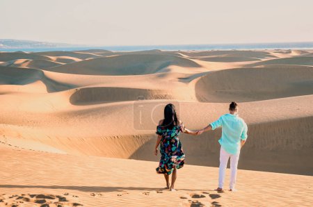 Photo for Couple walking at the beach of Maspalomas Gran Canaria Spain, men and woman at the sand dunes desert of Maspalomas Spain Europe during vacation holidays in Europe - Royalty Free Image