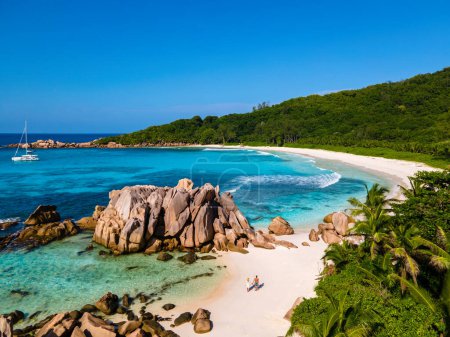Téléchargez les photos : Plage d'Anse Cocos, Île de La Digue, Seychelles, Drone vue aérienne de La Digue Seychelles vue aérienne d'une île tropicale, couple hommes et femmes marchant sur la plage au coucher du soleil lors de vacances de luxe - en image libre de droit