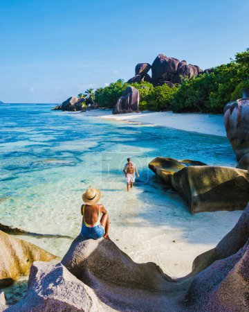 Téléchargez les photos : Anse Source dArgent beach, La Digue Island, Seychelles, couple hommes et femmes marchant sur la plage au coucher du soleil lors de vacances de luxe aux Seychelles La Digue Island - en image libre de droit