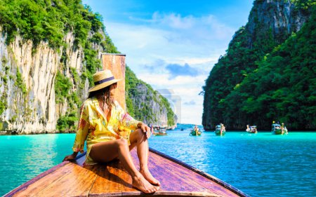 Photo for Asian women in front of a longtail boat at Kho Phi Phi Thailand, women in front of a boat at Pileh Lagoon with turqouse colored ocean during a boat trip to Maya Bay Koh Phi Phi - Royalty Free Image