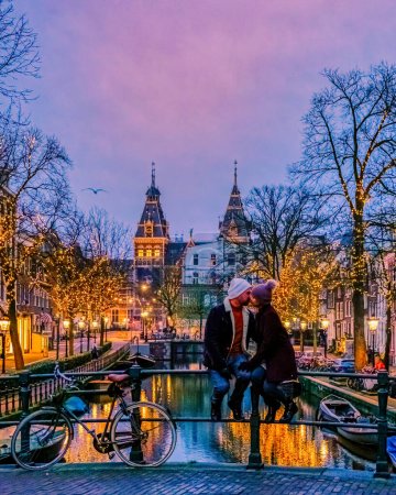 Foto de Pareja en un viaje a la ciudad de Amsterdam Países Bajos canales con luces de Navidad durante diciembre, canal centro histórico de Ámsterdam por la noche. Europa - Imagen libre de derechos