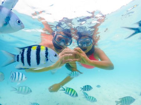 A young couple of men and a woman on a snorkeling trip at Samaesan Thailand. dive underwater with Nemo fishes in the coral reef sea pool. couple swim activity on a summer beach holiday 