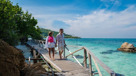 Foto de Un par de hombres europeos y una mujer asiática en un viaje en barco en Ko Kham Island Chonburi Samaesan Tailandia, una pareja caminando en un embarcadero de puente de madera en una isla tropical con ocen de color turquesa - Imagen libre de derechos