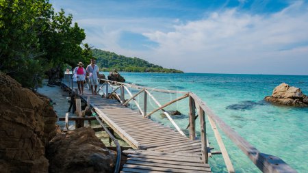 Téléchargez les photos : Un couple d'hommes européens et une femme asiatique lors d'une excursion en bateau à Ko Kham Island Sattahip Chonburi Samaesan Thaïlande, un couple à une jetée en bois sur une île tropicale avec ocen turqouse de couleur - en image libre de droit