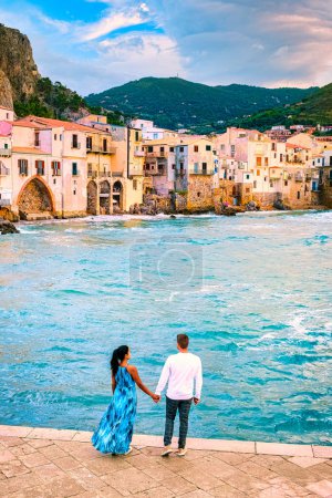 Photo for Couple of men and woman on vacation in Sicily visiting the old town of Cefalu, sunset at the beach of Cefalu Sicily, the old town of Cefalu Sicilia Italy - Royalty Free Image