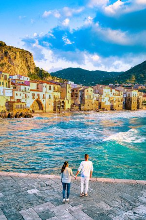 Téléchargez les photos : Couple d'hommes et de femmes en vacances en Sicile visitant la vieille ville de Cefalu Sicile Italie, coucher de soleil sur la plage de Cefalu Sicile, la vieille ville de Cefalu Sicile Italie - en image libre de droit