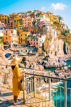 Foto de Mujer asiática con un sombrero con vistas a Manarola Cinque Terre Italia, Manarola Village Cinque Terre Coast Italia. Manarola es una hermosa ciudad colorida de La Spezia, Liguria uno de los cinco Cinque Terre - Imagen libre de derechos