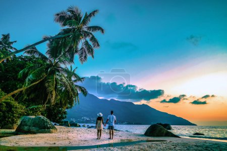 Foto de Seychelles islas tropicales, Isla Praslin Seychelles con pareja caminando por la playa tropical con palmeras durante el atardecer - Imagen libre de derechos