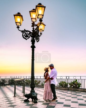 Photo for Taormina Sicily Belvedere of Taormina and San Giuseppe church on the square Piazza IX Aprile in Taormina Sicily Italy. couple under lantern during sunrise hugging together romantic scenery - Royalty Free Image