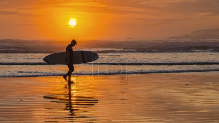 Photo for Tofino Beach Vancouver Island Pacific rim coast during sunset, surfers with surfboard during sunset at the beach of Tofino, surfers silhouette Canada Vancouver Island Tofino Long beach - Royalty Free Image