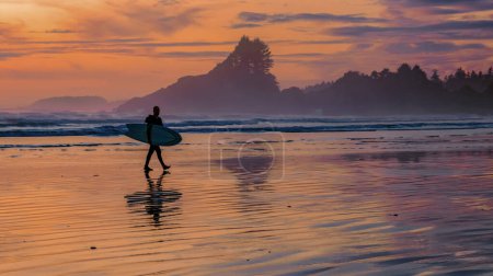 Téléchargez les photos : Tofino beach Vancouver Island Pacific rim coast during sunset, surfeurs avec planche de surf au coucher du soleil à la plage, surfeurs silhouette Canada Vancouver Island Tofino Long beach - en image libre de droit